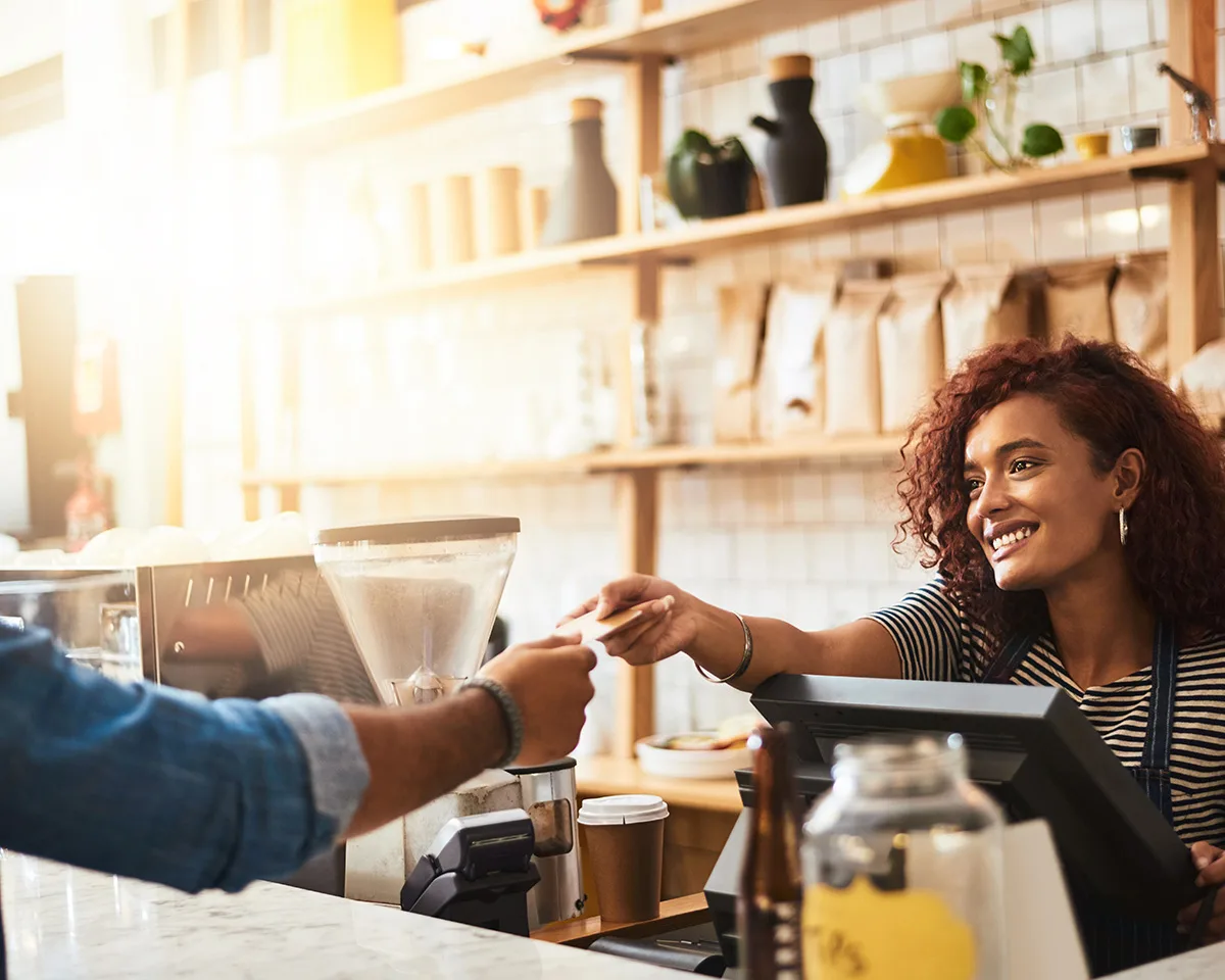 Barista taking a card payment at a café counter with an Odyssey Restaurant POS terminal